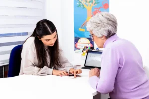Sprachtherapie für Erwachsene: Therapeutin arbeitet mit einer älteren Patientin am Tablet